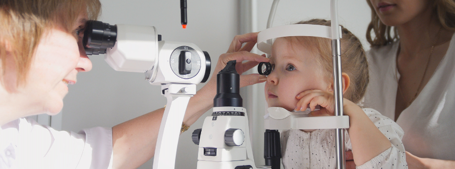 Oculista che visita una bambina alla lampada a fessura